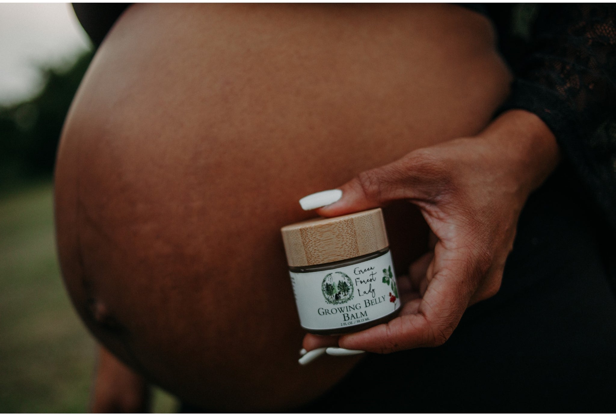 Picture of a pregnant belly holding the Growing Belly Balm in front of it.
